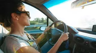 Kobieta za kierownicą w skupieniu prowadzi auto.
