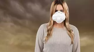kobieta w masce anty smogowej na tle chmur pyłu