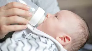 Karmienie noworodka butelką. Mama karmi dziecko mlekiem z butelki.