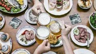 kuchnia czeska, 3 ręce z kuflami piwa nad stołem jedzeniem czeskim
