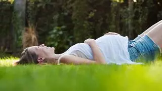 Kobieta w ciąży leży na trawie