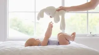 Niemowlak leży na łóżku