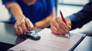 Mężczyzna i kobieta podpisują umowę na leasing samochodu.