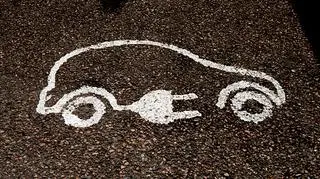 Na asfalcie narysowany obrys auta z wtyczką elektryczną