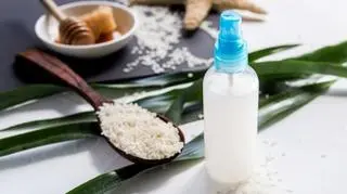 Butelka z atomizerem wypełniona białym płynem, obok drewniana łyżka z ryżem