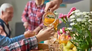 Kompot owocowy w dzbanku. W tle rodzina przy stole