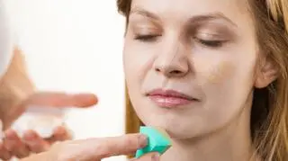 zblizenie na twarz mlodej kobiety malowanej podkladem nawilzajacym gabeczka