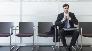 Mężczyzna w garniturze siedzi na krześle. Oczekuje na rozmowę o pracę.