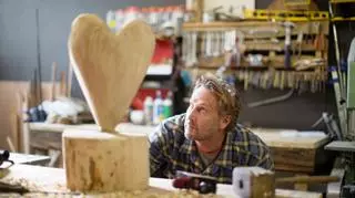 mezczyzna w pracowni rzezbi z drewna rzezba serca na stole