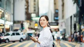 Pani w okularach z telefonem w dużym mieście