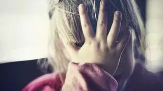 Smutna dziewczynka zakrywająca twarz dłonią 