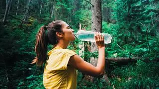 dziewczyna pije wodę demineralizowaną w lesie