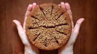 Okrągły chleb gryczany trzymany w dłoniach 