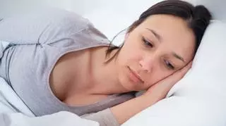 Smutna młoda kobieta leży na łóżku
