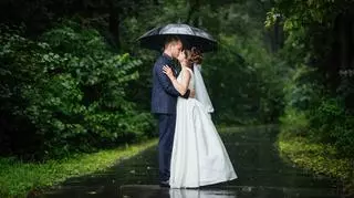 Młoda para całuje się stojąc w deszczu pod parasolką