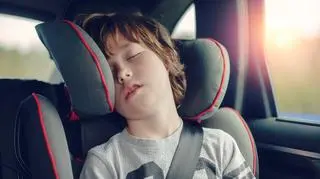 Kilkuletni chłopiec śpi w foteliku samochodowym