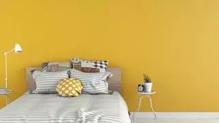 Łóżko w sypialni, żółta ściana