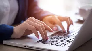 Kobieta pisze na komputerze. 
