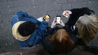 3 osoby ze smartfonami na chodniku widziane z góry