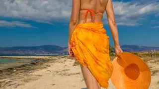 Kobieta w chuście na biodrach chodzi po plaży