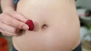 Kobieta w pierwszym trymestrze ciąży trzyma owoc wielkości płodu