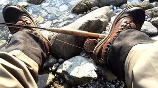 Spodnie wędkarskie i buty wędkarskie, wędka nad rzeką