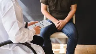 mezczyzna z impotencja siedzi u lekarza trzyma sie za krocze