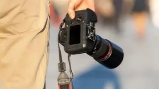 meska dlon trzymajaca lustrzanke pelnoklatkowa na wysokosci uda zblizenie