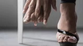 kobieca dłoń dotykająca stopy wysoki obcas naga stopa