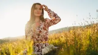 Kobieta w długiej kwiecistej sukience na łonie natury