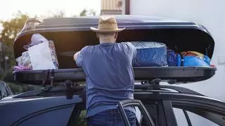 Mężczyzna ładujący bagaże do boxu samochodowego.