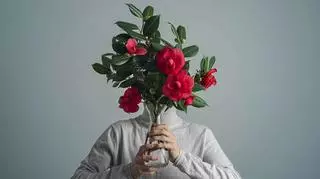 Mężczyzna zakrywa twarz kwiatami 
