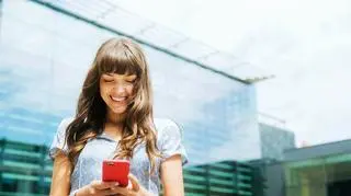 młoda kobieta, która trzyma telefon komorkowy 