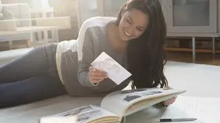 Kobieta leży na podłodze i przegląda zdjęcia ze ślubu.