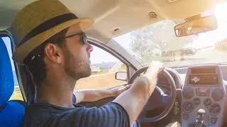 Mężczyzna w przeciwsłonecznych okularach prowadzi samochód