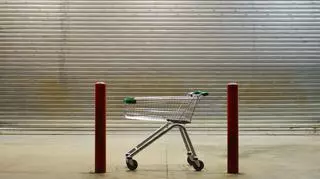 Wózek z supermarketu na tle zamkniętej rolety sklepowej