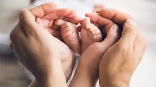 stopy dziecka i dłonie osoby dorosłej