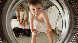 Chłopiec w bokserkach zagląda do pralki