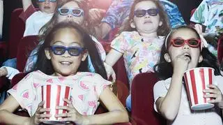 dzieci w kinie jedzą popcorn