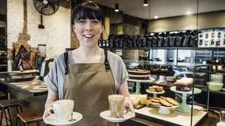 Kobieta pracuje w kawiarni i podaje kawę