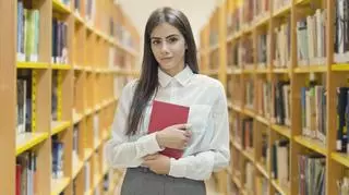 Uczennica w białej koszuli w szkolnej bibliotece