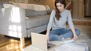 Kobieta w domu pracuje na laptopie i przegląda dokumenty