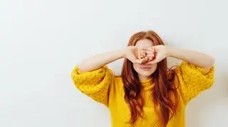 kobieta w żółtym swetrze zasłania spuchnięte oczy