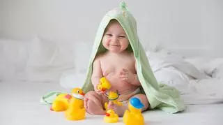 Półroczne niemowlę siedzi w ręczniku i się bawi