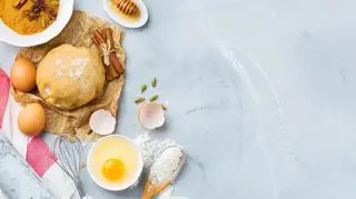 Przygotowania do pieczenia ciasta - jajka, mąką, miód, zagniecione ciasto.