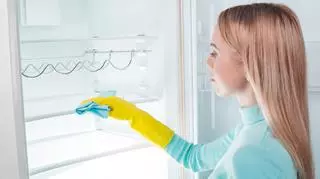 Młoda kobieta czyści lodówkę