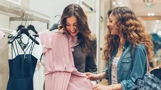 Uśmiechające się kobiety oglądają różową sukienkę kopertową