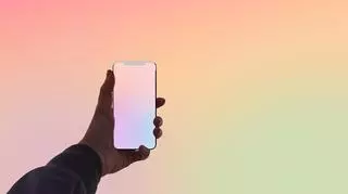smartfon w dłoni na pastelowym tle, aktualizacja Apple