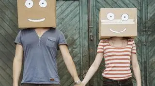 Para trzymająca się za ręce z zabawnymi kartonami na głowie 