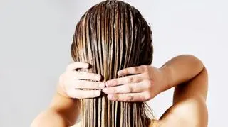 kobieta nakładająca na swoje długie włosy odżywkę